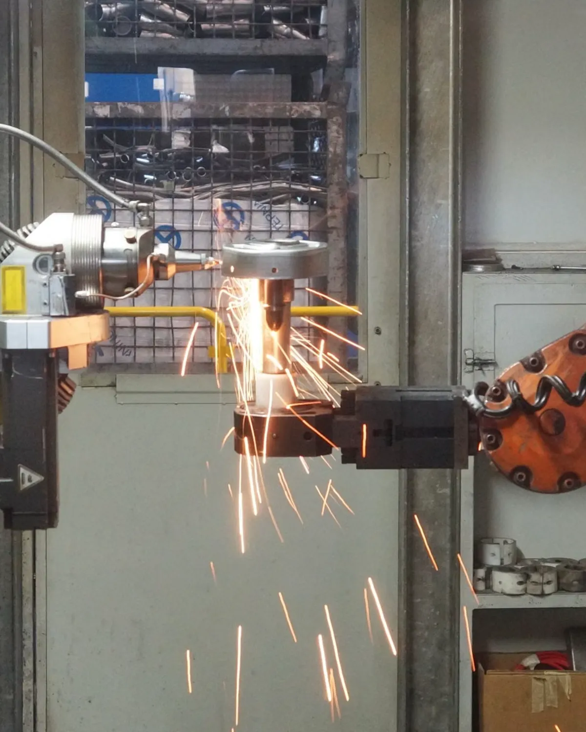 Robotic welding cell throwing sparks on a plant floor